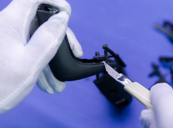 worker is trimming plastic parts